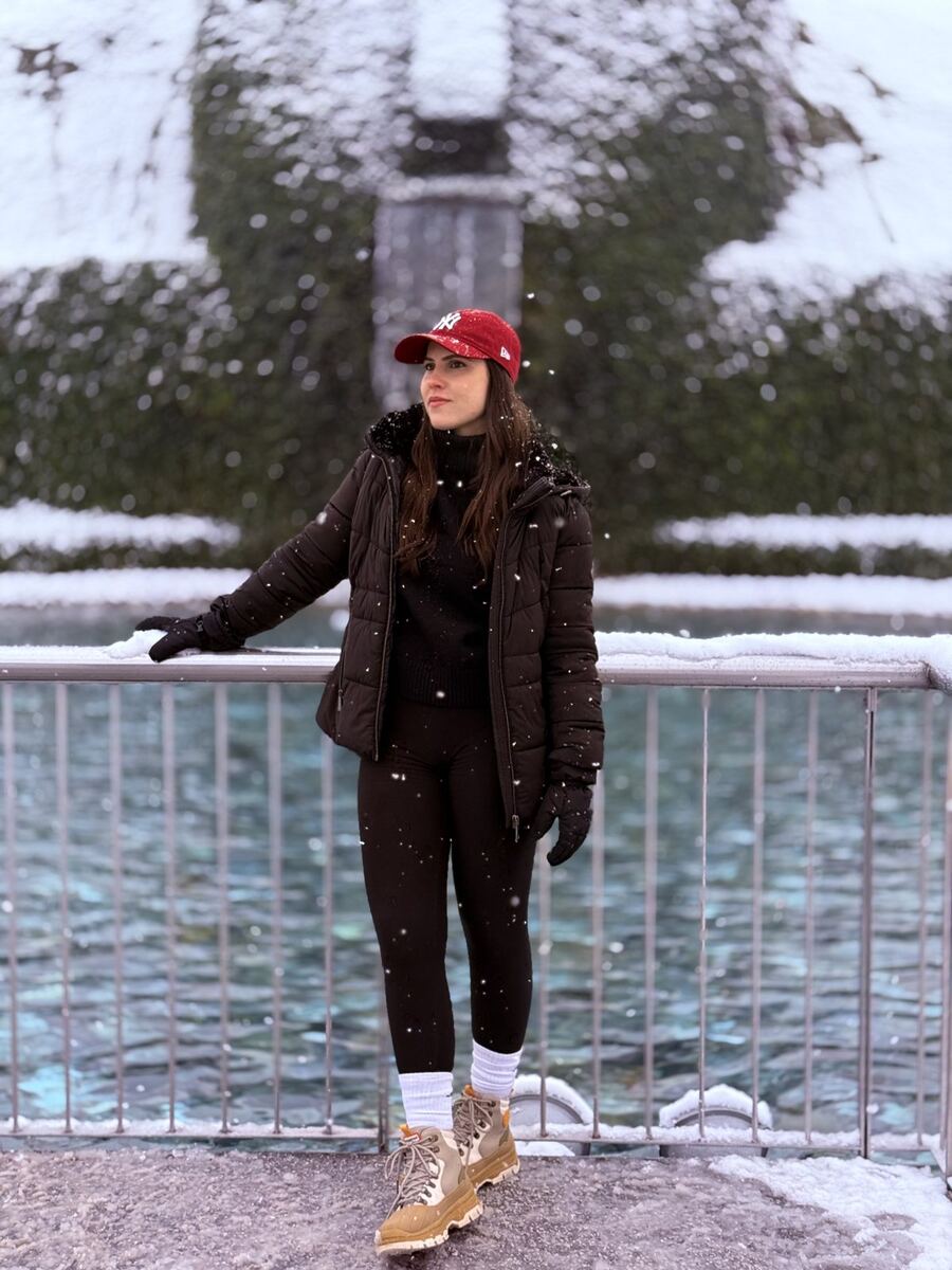 Miriã de boné vermelho numa ponte, com neve caindo