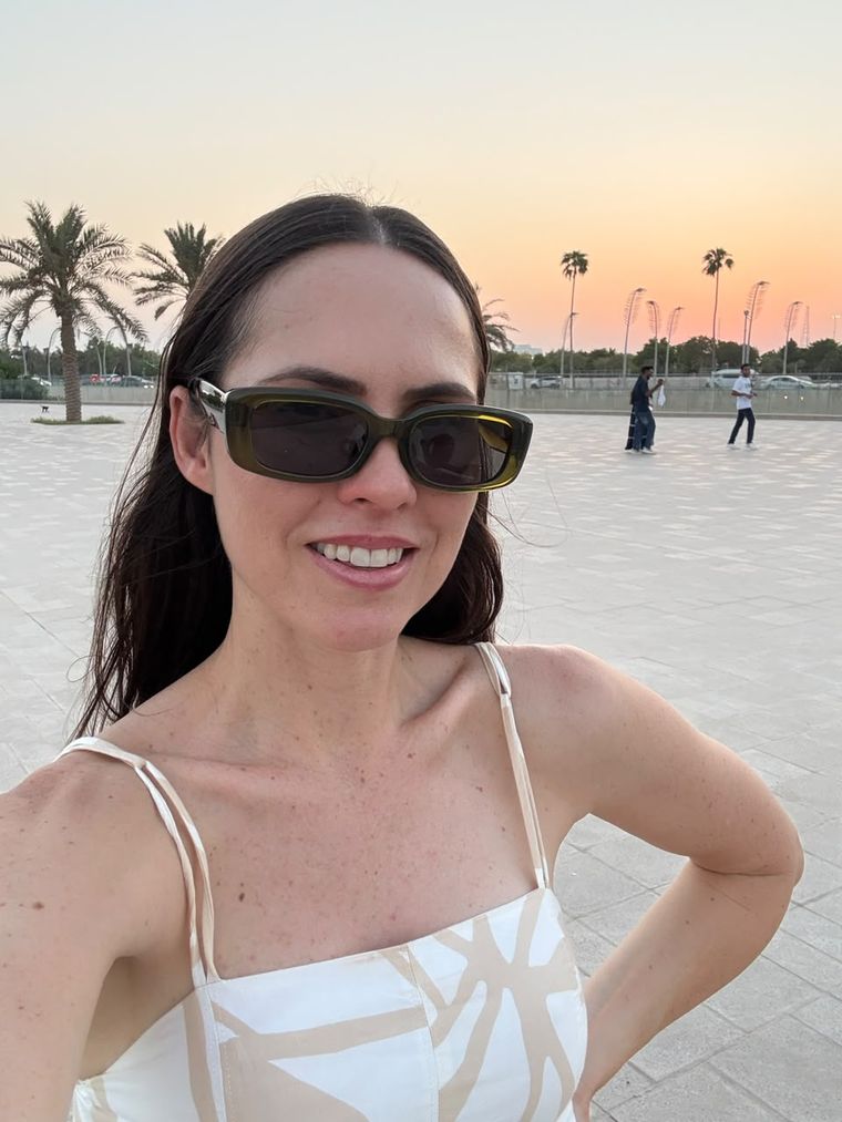 Miriã sorrindo ao entardecer, de óculos escuros